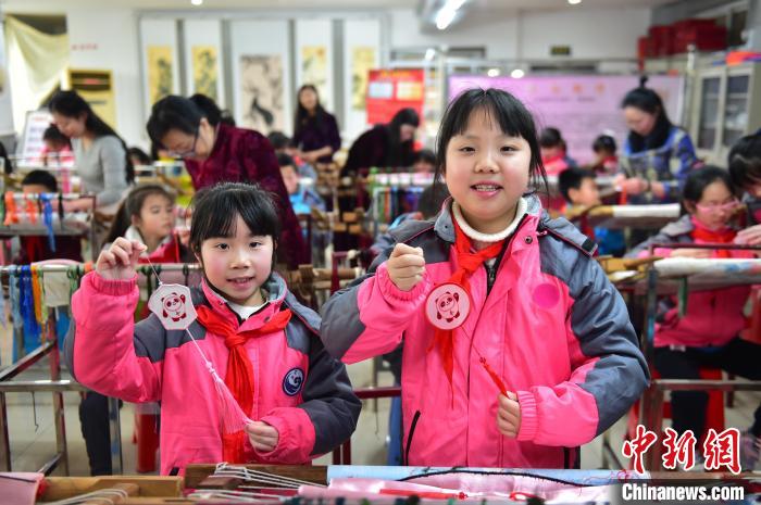 圖為小學(xué)生展示繡制好的2022年北京冬奧會吉祥物“冰墩墩”形象。　喻云亮 攝