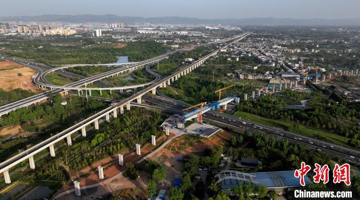 航拍正在建設(shè)的跨越成都繞城高速公路連續(xù)梁施工現(xiàn)場，旁邊依次為已運營的成渝高速鐵路和機(jī)場高速公路?！⒅铱?攝