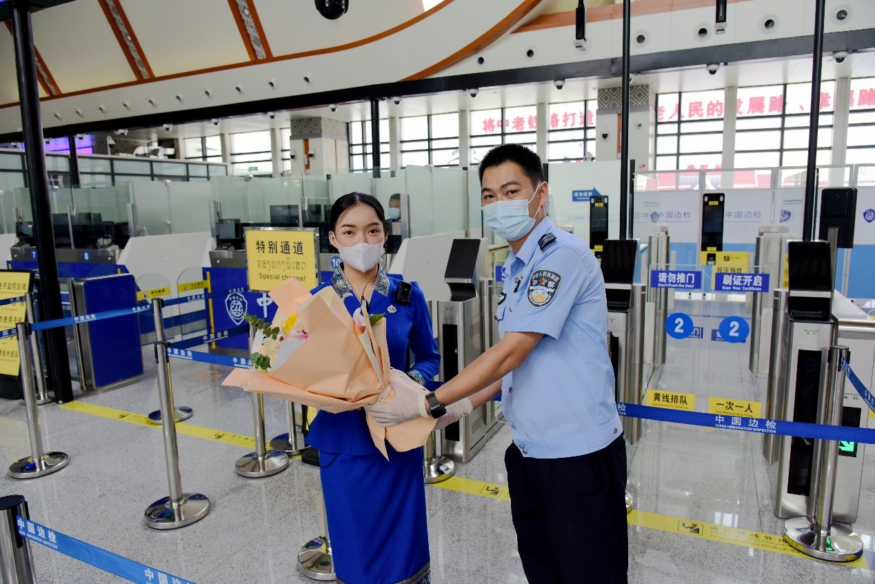 磨憨出入境邊防檢查站民警為中老鐵路第100萬名出入境旅客，D888次國際旅客列車?yán)蠐爰藙?wù)員森達(dá)拉·妮緹婭（Sengdala Nitiya），送上鮮花。黃遠(yuǎn)飛 攝