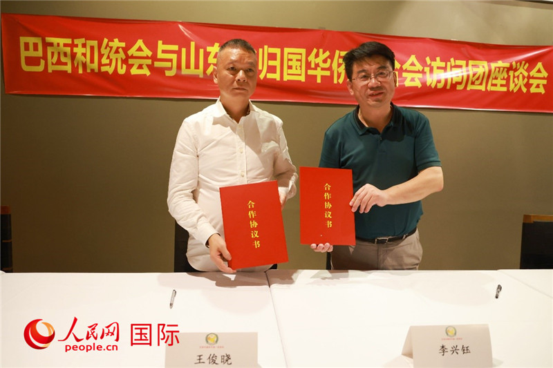 中國僑聯(lián)副主席、山東省僑聯(lián)主席李興鈺（右）與巴西和統(tǒng)會會長王俊曉簽署合作協(xié)議書。人民網(wǎng)記者 陳海琪攝