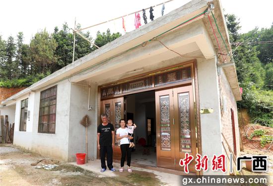 7月4日，在廣西柳州市融安縣大坡鄉(xiāng)崗偉村，脫貧戶肖裕安（左）與妻子、外孫在改造后的房屋前合影。覃慶和 攝