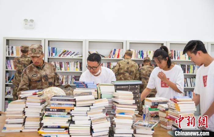 圖為志愿者們和邊防戰(zhàn)士整理圖書。　劉曉東 攝