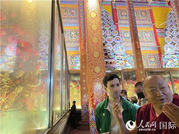 7月25日，省級非物質(zhì)文化遺產(chǎn)項目塔爾寺酥油花的代表性傳承人朋措堅參（右）在塔爾寺酥油花館講解酥油花的制作過程。人民網(wǎng) 謝瑩攝