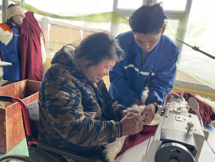 扎西奪爾登幫助殘疾員工裁剪。阿壩州文明辦供圖