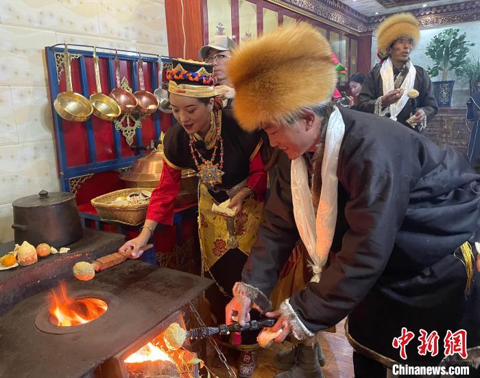 圖為人們在火上烤節(jié)日美食“結(jié)達(dá)”?！∪轿木?攝