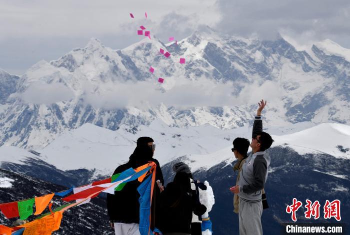 圖為5月14日，游客在西藏林芝色季拉山觀景臺拋灑“隆達(dá)”(風(fēng)馬旗，藏族民眾的一種祈福方式)?！±盍?攝